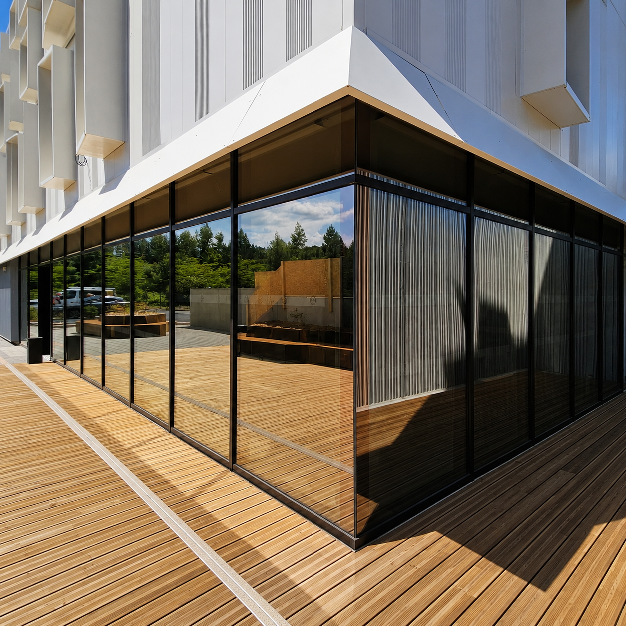 Aluminium glazed façade at the corner of a building, with a timber terrace